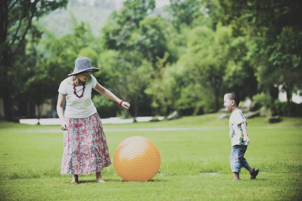 Child playing with a big ball with mother outside