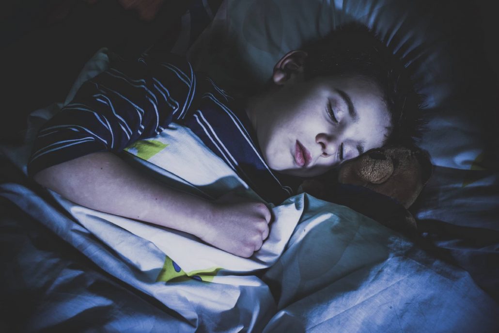 Sleeping child with his toy bear.